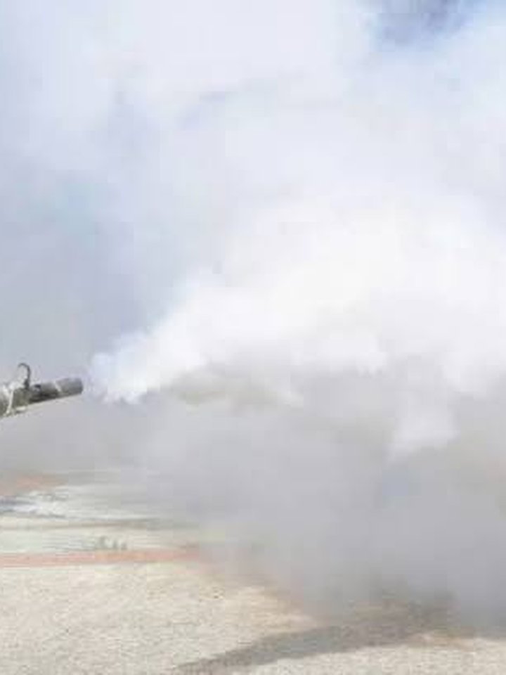 Technician fumigating an outdoor commercial area with fogging equipment